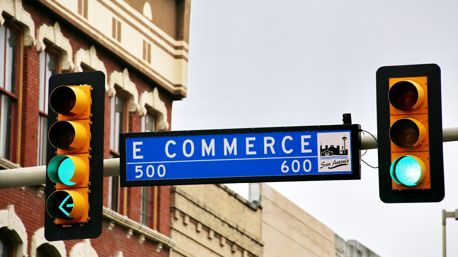 E-Commerce sign with a traffic light with a street sign hanging from it's side